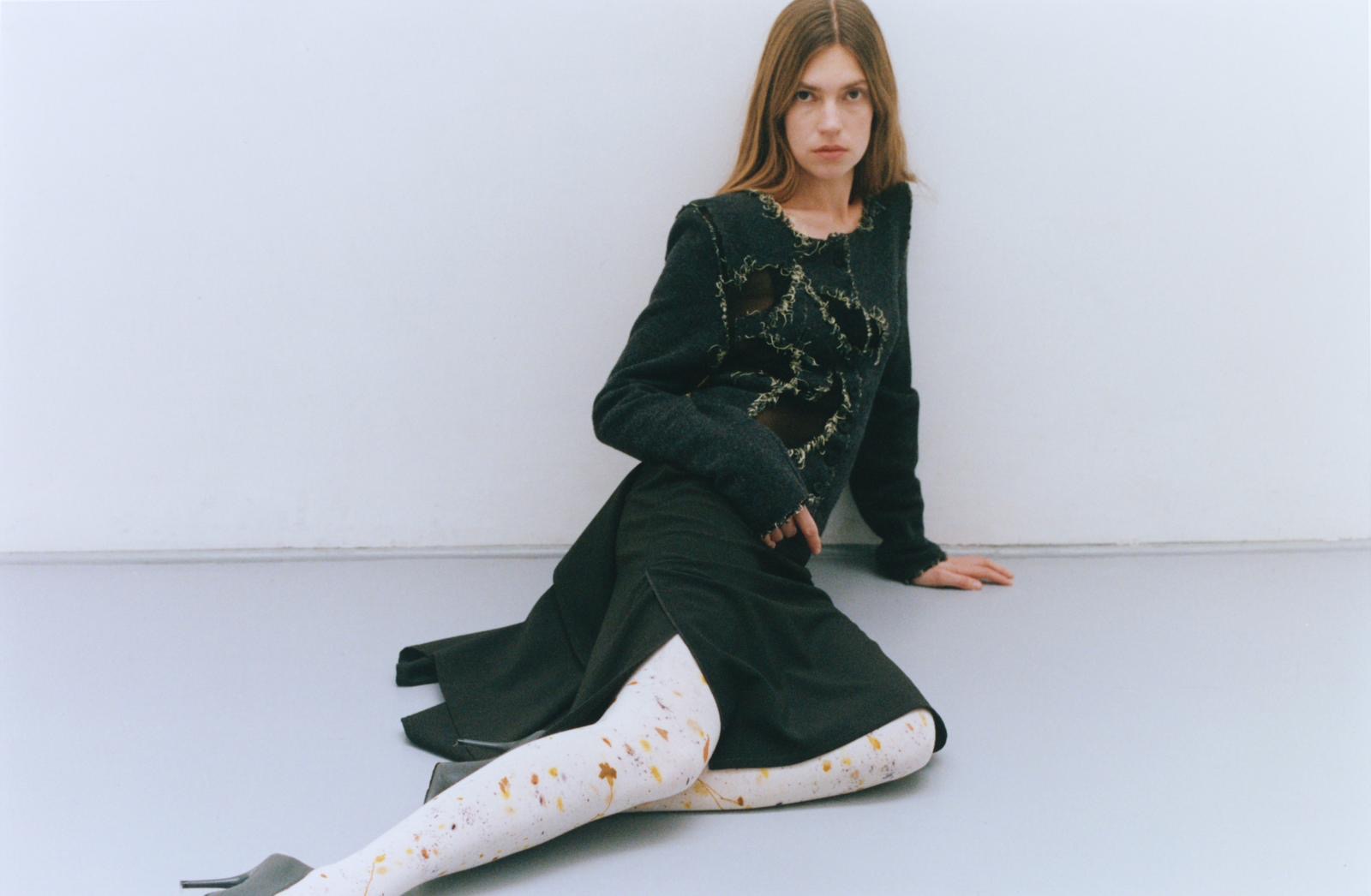 femme-assise-au-sol-tenue-robe-verte-foncée-trou-fil debordant-forme-fleur