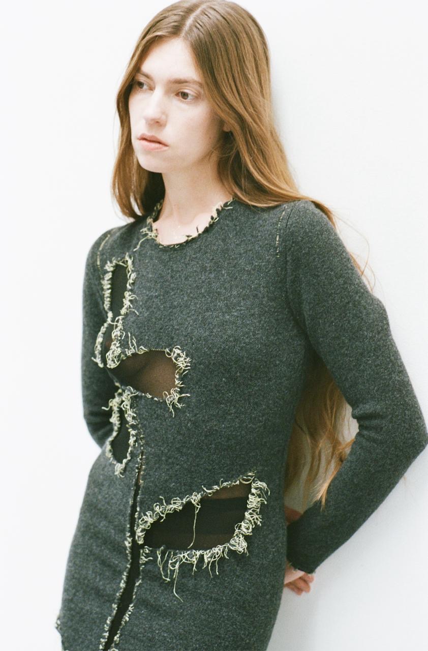 femme-adossée-cheveux-long-mur-tenue-robe-verte-foncée-trou-fil debordant-forme-fleur